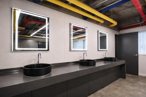 a row of sinks in a bathroom with two mirrors at JE JA RI Stay in Seoul