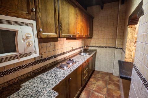 a kitchen with a sink and a microwave at Alojamientos Rurales Benarum con Spa in Alpujarra De La Sierra