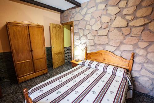 a bed in a room with a stone wall at Alojamientos Rurales Benarum con Spa in Alpujarra De La Sierra