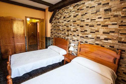 a bedroom with two beds and a brick wall at Alojamientos Rurales Benarum con Spa in Alpujarra De La Sierra