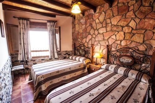 four beds in a room with a stone wall at Alojamientos Rurales Benarum con Spa in Alpujarra De La Sierra