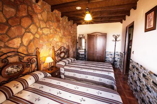 three beds in a room with a stone wall at Alojamientos Rurales Benarum con Spa in Alpujarra De La Sierra