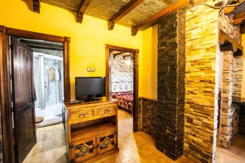 a room with a tv on a wooden dresser in front of a wall at Alojamientos Rurales Benarum con Spa in Alpujarra De La Sierra