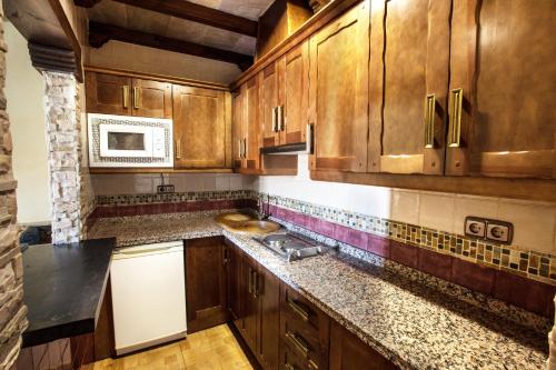 a kitchen with wooden cabinets and a microwave at Alojamientos Rurales Benarum con Spa in Alpujarra De La Sierra