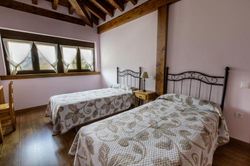 two beds in a room with two windows at La Dobra de liebana in Cambarco