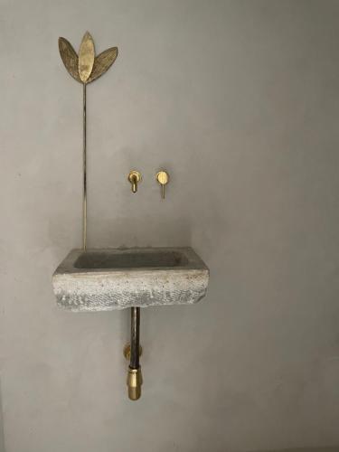 a stone sink on a wall with two gold fixtures at La Saracina in Pienza