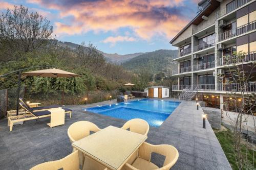 a hotel patio with a pool and tables and chairs at Echor Himalayan Aurum Resort & Spa, Manali in Manāli