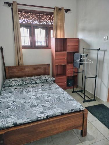 a bedroom with a wooden bed with a dresser and a window at DenbyD in Tennekumbura