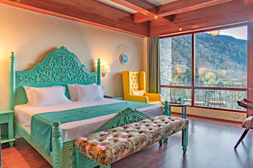 a bedroom with a bed and a chair and a window at Echor Himalayan Aurum Resort & Spa, Manali in Manāli