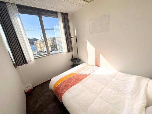 a bedroom with a bed and a large window at Magokoro House 201 in Nishiizu