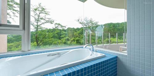 a bath tub in a bathroom with a window at Scenery Resort Suruga in Numazu