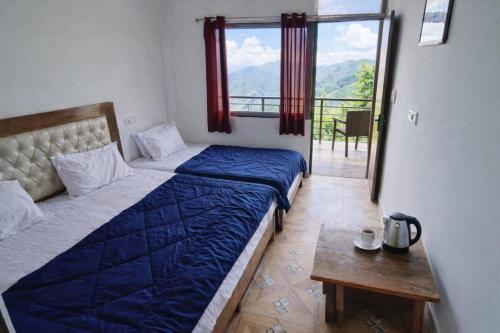 a bedroom with two beds and a table and a window at shiv shankar resort and hotel in Phata