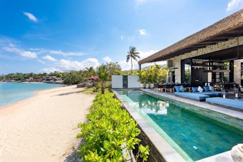an infinity pool next to the beach at a resort at Clay Beach Samui - Beachfront Villas in Bophut