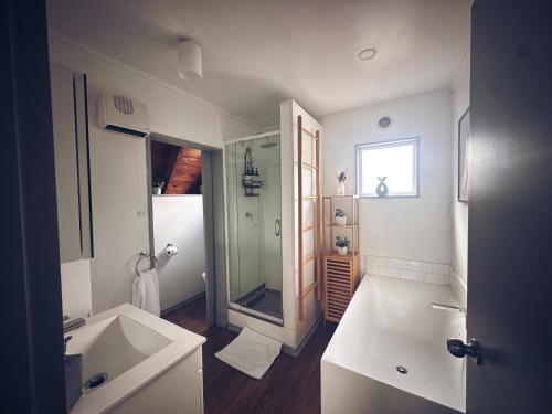a white bathroom with a shower and a sink at Aurora A-Frame Twizel in Twizel