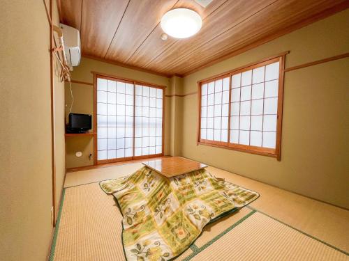 a room with a table in the middle of a room with windows at Chouchinya in Nozawa Onsen