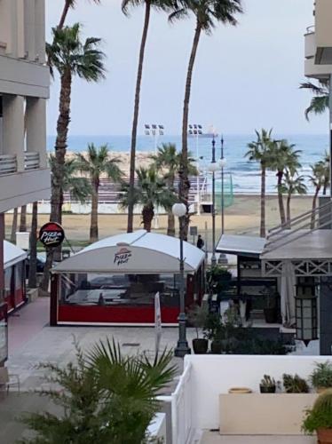 a view of a beach with palm trees and the ocean at Larnaca Beach Apartment in Larnaca