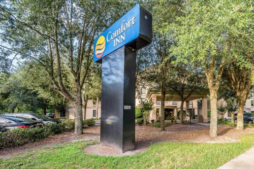 a sign for a hotel on a pole in the grass at Comfort Inn University in Gainesville
