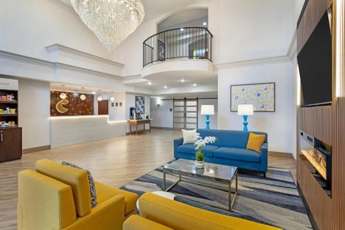 a living room with a blue couch and yellow chairs at Comfort Suites East Brunswick - South River in East Brunswick