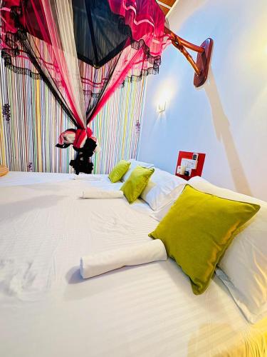 a large white bed with green pillows in a room at Freedom Cottage & Safari in Tissamaharama