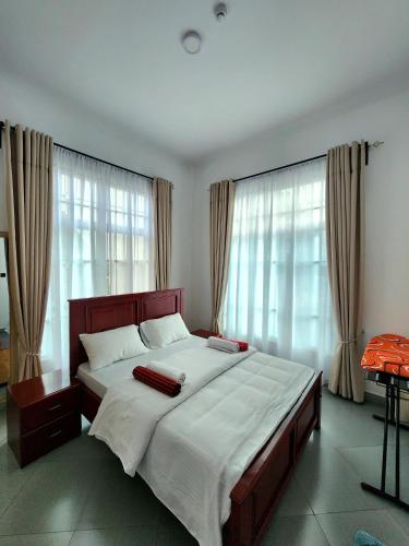 a bedroom with a large bed with white sheets and windows at Karibu Haven Apartments in Arusha