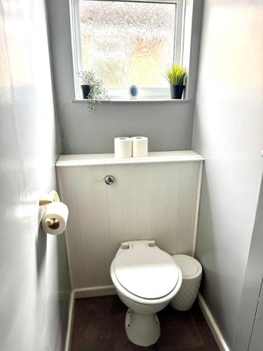 a small bathroom with a toilet and a window at Spacious House - Parking - Pool Table in Balderton
