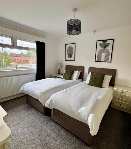 a bedroom with two beds and a window at Spacious House - Parking - Pool Table in Balderton