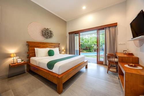 a bedroom with a bed and a television and a desk at Cove Ayuna in Canggu