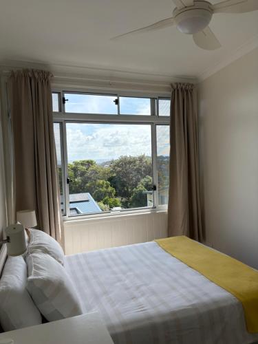 a bedroom with a bed and a large window at Shelly Beach Townhouse in East Ballina