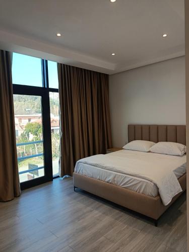 a bedroom with a bed and a large window at Rezidenca Pahumi 2 in Durrës