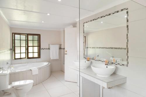 a white bathroom with two sinks and a tub and a toilet at Ardmore Guest Farm in Champagne Valley