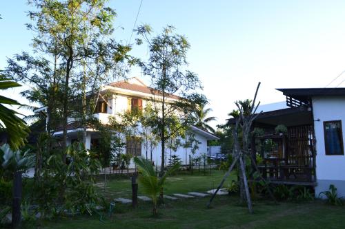 a white house with trees in the yard at Baan Suan La Moon in Chiang Khan