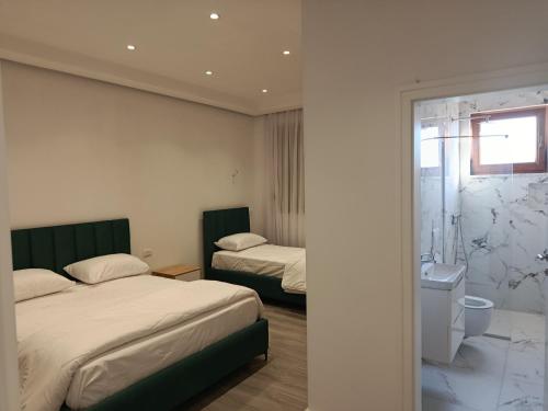 a hotel room with two beds and a bathroom at Rezidenca Pahumi 2 in Durrës