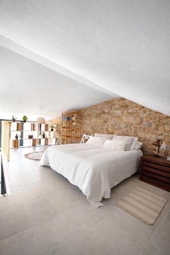 a bedroom with a large white bed and a stone wall at O Cabanel in Fisterra