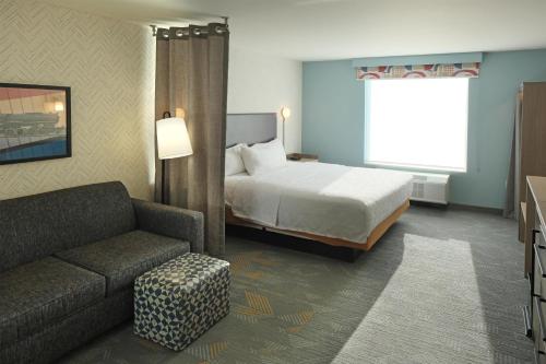 a hotel room with a bed and a couch at Home2 Suites By Hilton Lima in Lima
