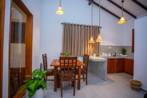 a dining room with a table and chairs and a kitchen at The Clouds Ahangama in Ahangama