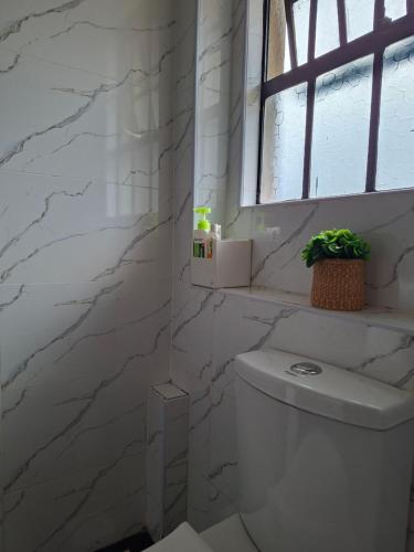 a white bathroom with a toilet and a window at Pearl Apartment Ruaka in Ruaka