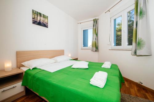 zielone łóżko w białym pokoju z oknami w obiekcie Rainbow apartments w mieście Zadar