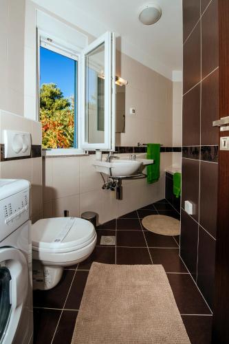 a bathroom with a toilet and a sink and a window at Rainbow apartments in Zadar