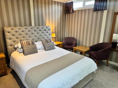 a hotel room with a large bed and two chairs at The Dog & Partridge Country Inn in Ashbourne