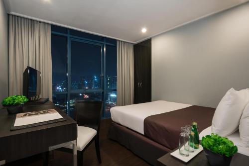 a hotel room with a bed and a desk and a window at Astoria Plaza in Manila