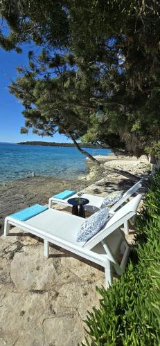 a white bench sitting on a beach next to the water at Villa Ružmarin in Lovište