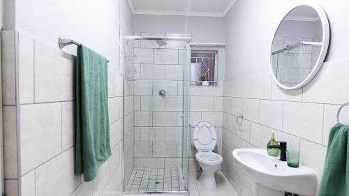a bathroom with a toilet and a sink and a mirror at Deluxe on Main in Roodepoort