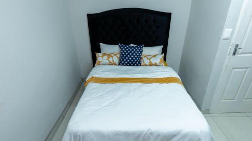 a small bed with a black headboard and pillows on it at Deluxe on Main in Roodepoort