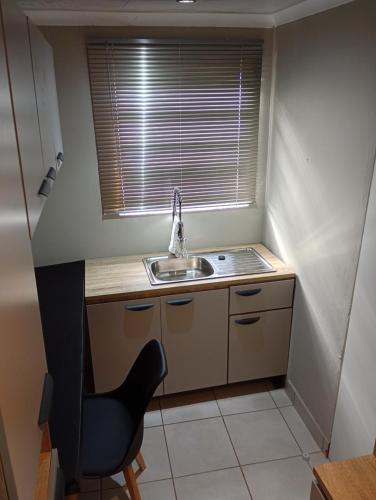 a small kitchen with a sink and a chair at Ashdown BnB in Pietermaritzburg