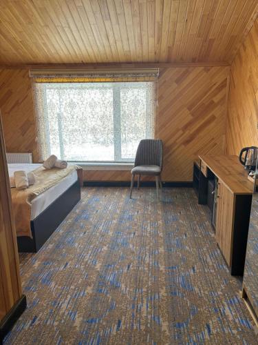 a bedroom with a bed and a window and a chair at Şəki Yaylası Hotel in Sheki