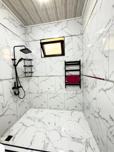 a bathroom with white marble walls and a window at Qax home in Qax
