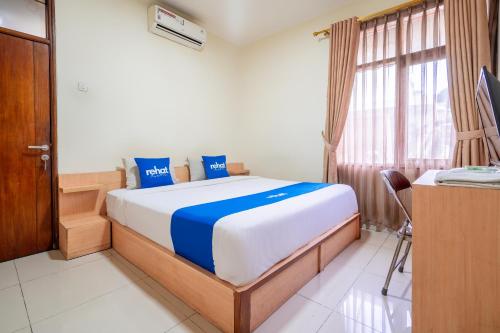 a bedroom with a bed and a desk and a window at Rehat at Hotel Kurnia Karapitan in Bandung