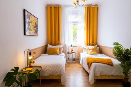 a room with two beds and a window with yellow curtains at Ferienwohnung Gründerhaus in Brandenburg an der Havel