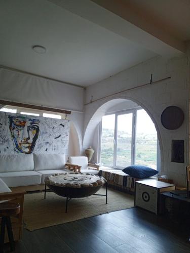 a living room with a couch and a large window at Greek Style Bed & Breakfast in Al Manashsh