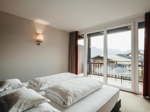 two beds in a room with a large window at Hotel Chesa Monte 4Sterne Superior in Fiss